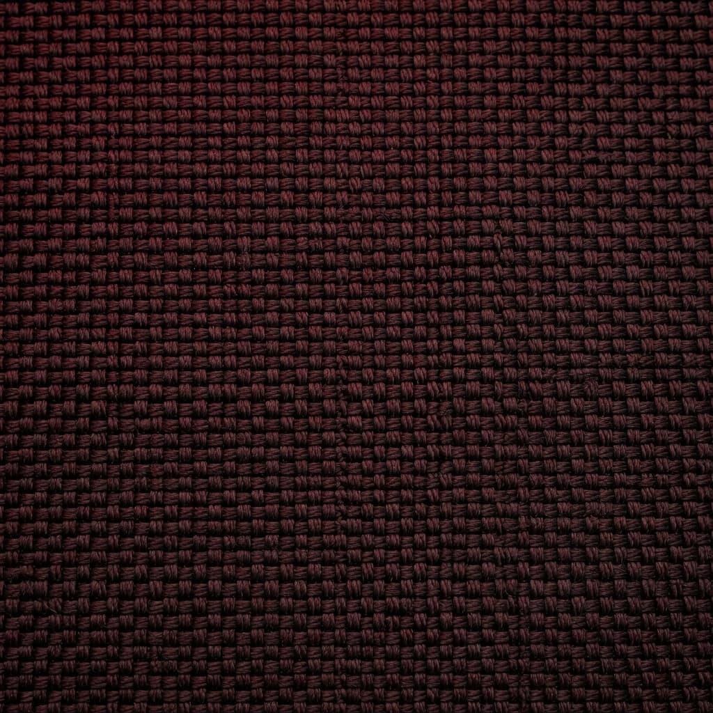 A close-up view reveals the intricate, robust weave of dark, heat-resistant aramid material. Deep red ambient lighting highlights the texture, emphasizing the structural integrity and rugged nature of the protective cloth.