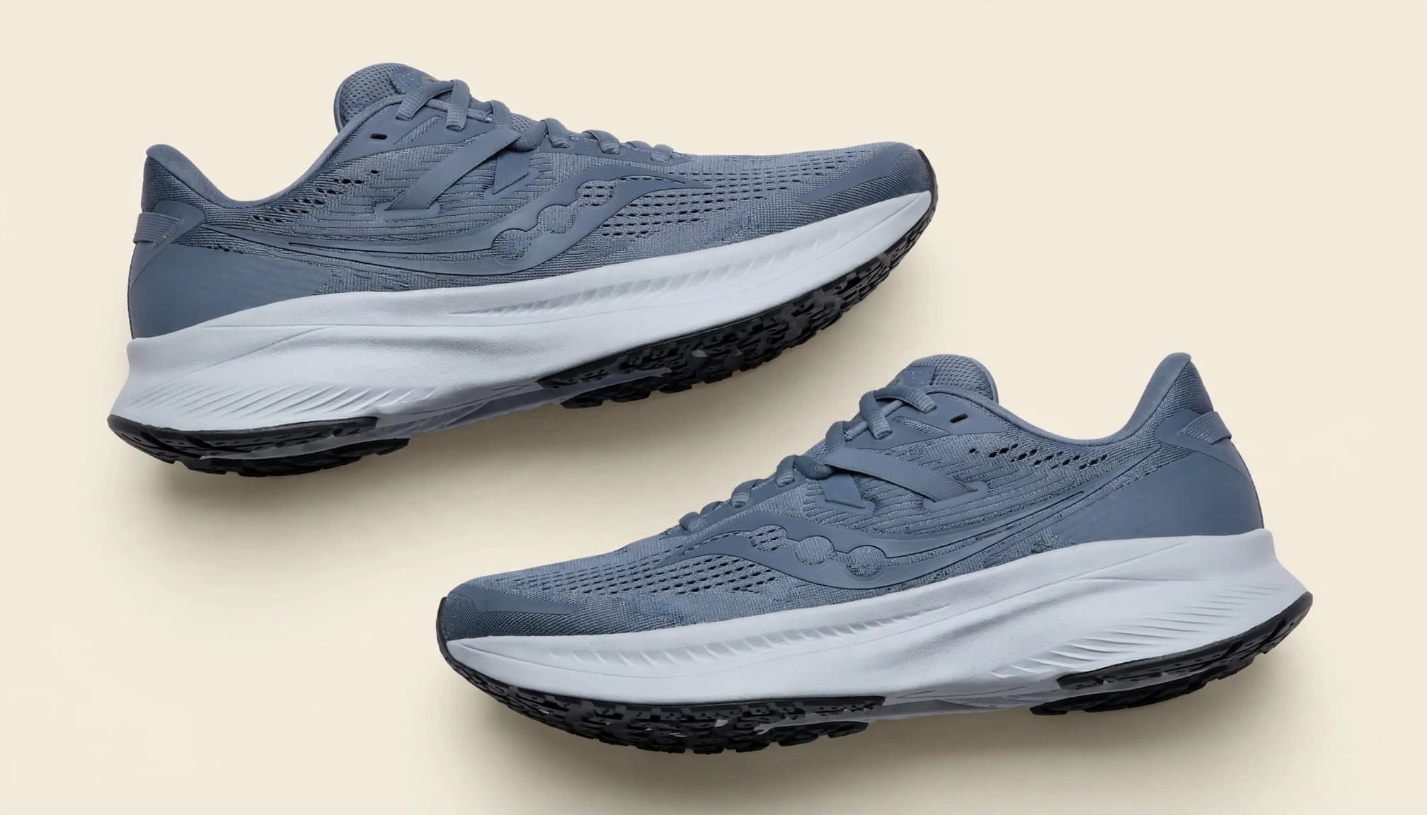 A pair of stability running shoes on a pale beige surface.