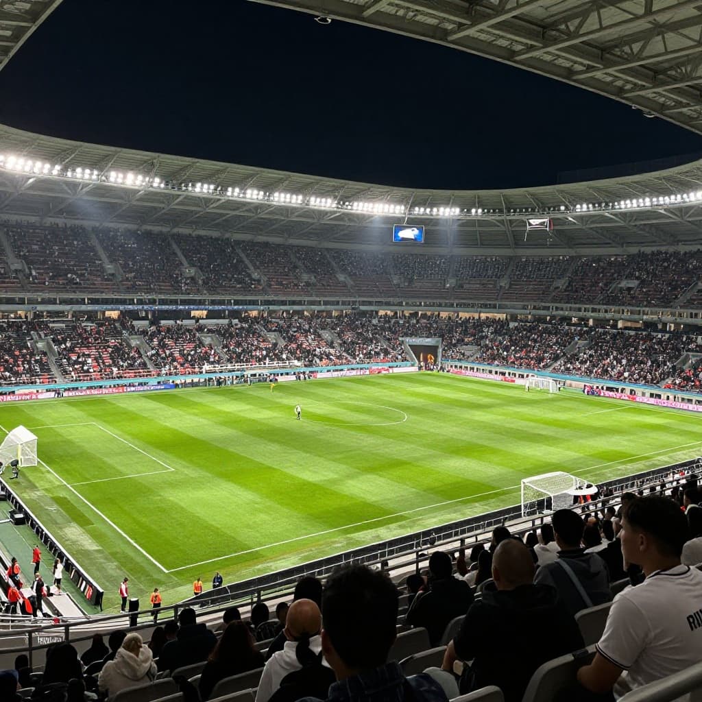 A vibrant football stadium illuminated by bright floodlights under the night sky.