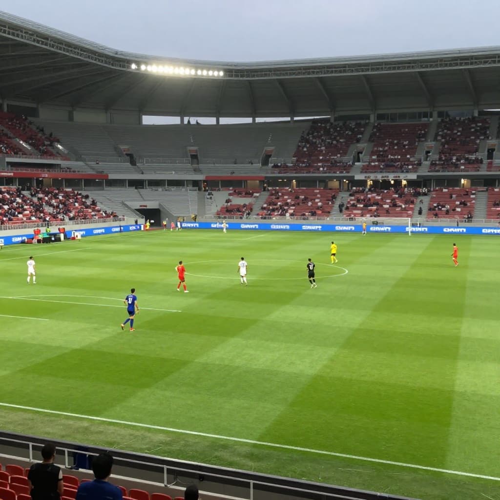 Two national football teams compete on a bright green field inside a massive stadium.