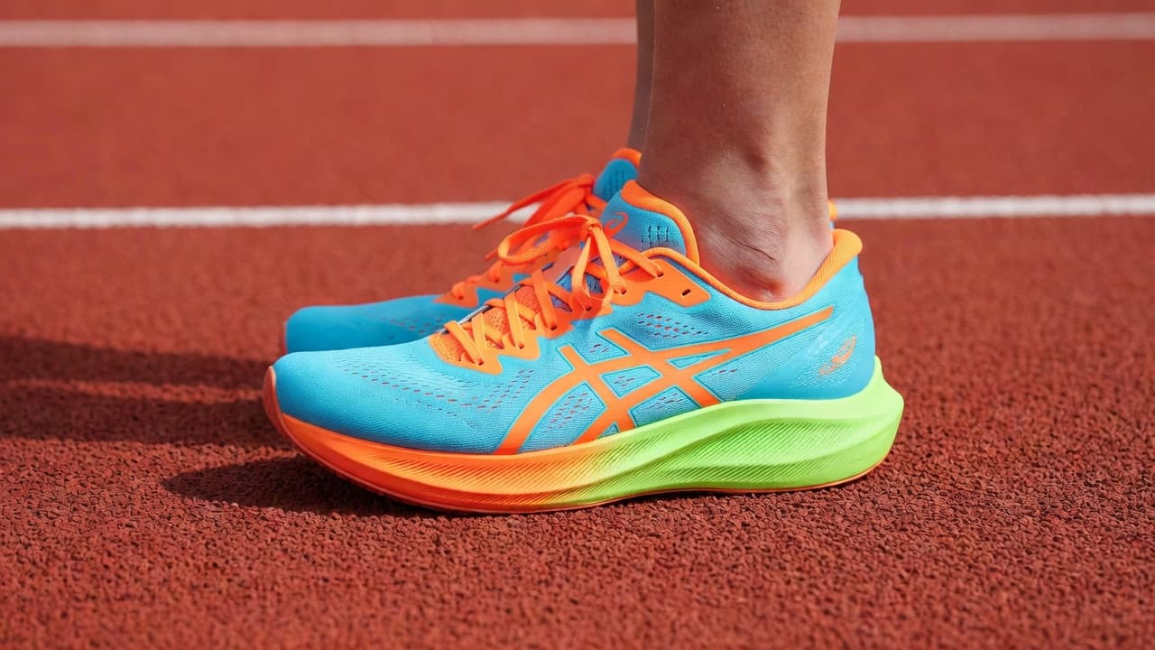 A close-up side profile captures the vibrant fabric of running shoes on a track. The synthetic mesh hugs the midfoot and toe box, showcasing a precise fit during daytime use.