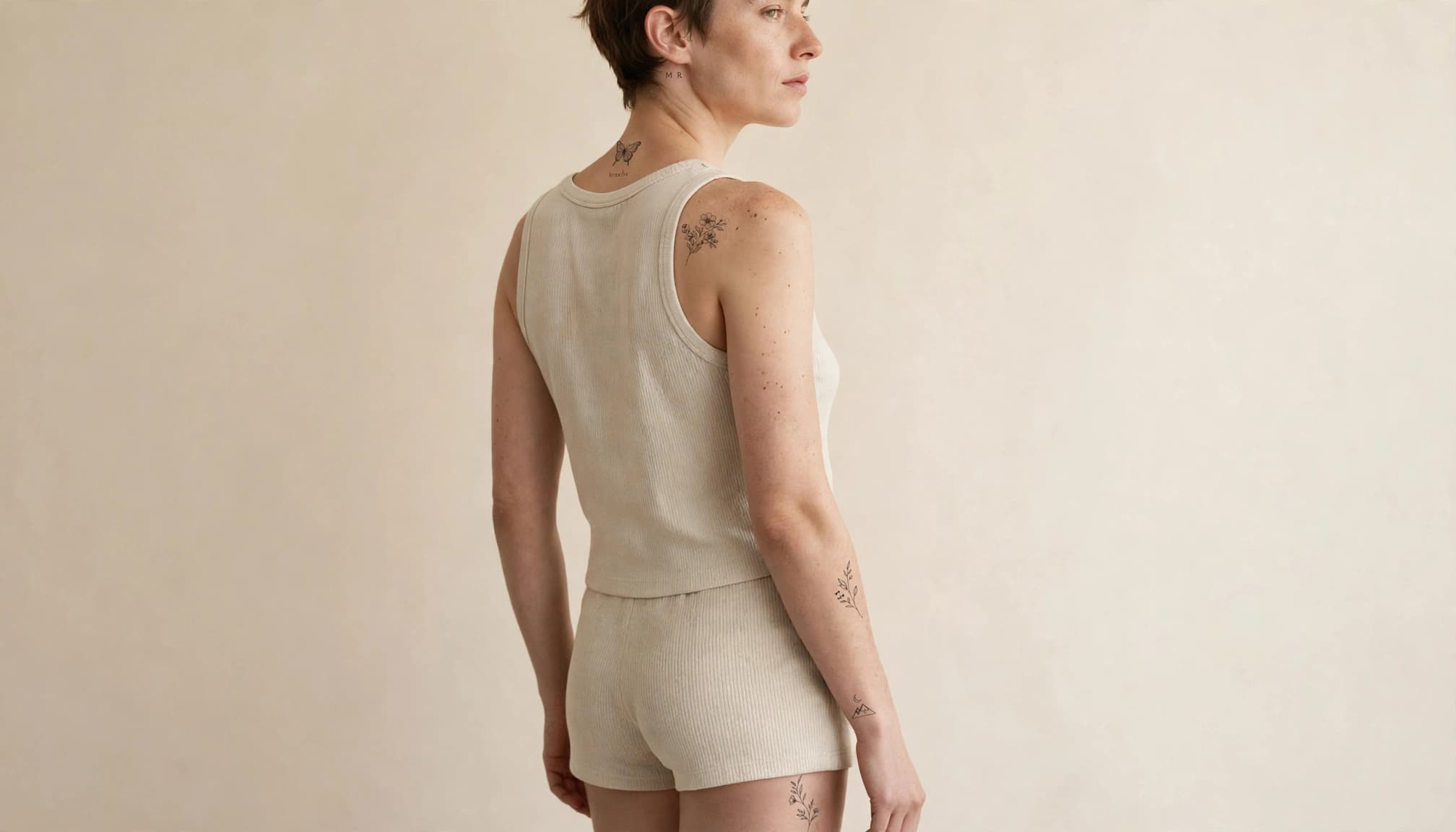 A figure shows small fine-line tattoos on the shoulder, wrist, forearm, and thigh.
