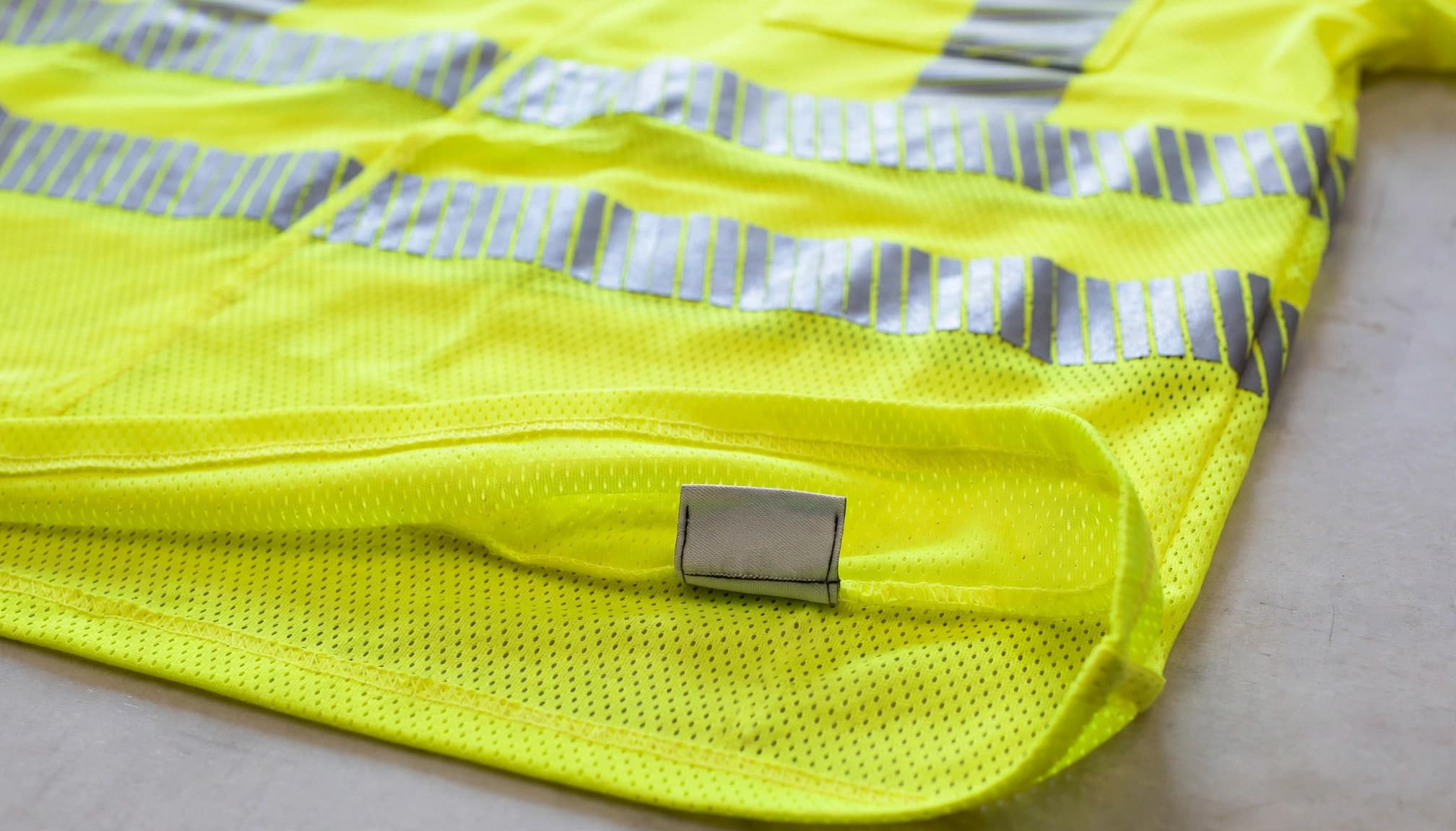Fluorescent safety shirt showing breathable fabric, reflective trim, and a sewn label.