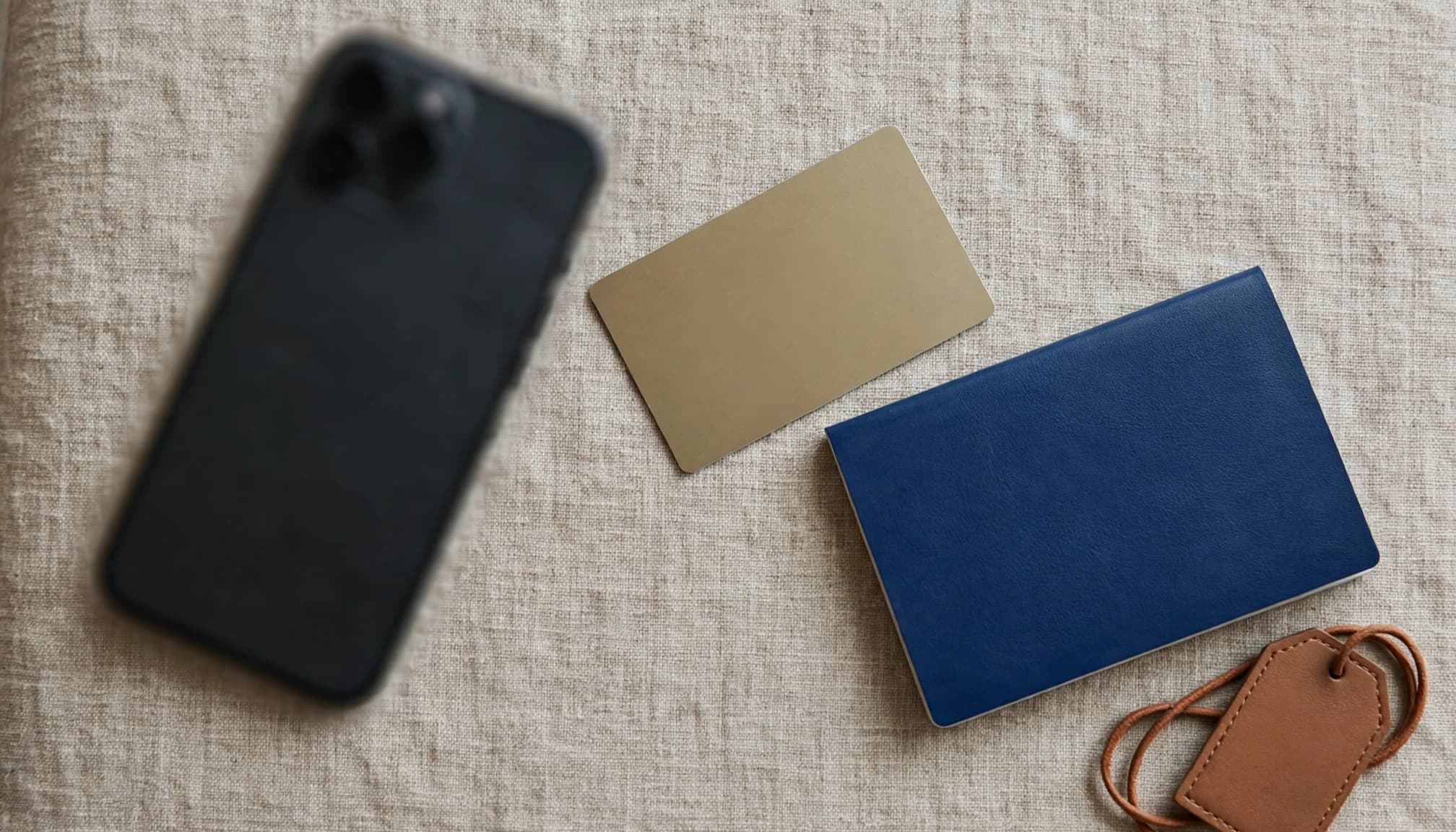 A smartphone, payment card, passport, and luggage tag on an airport lounge table.