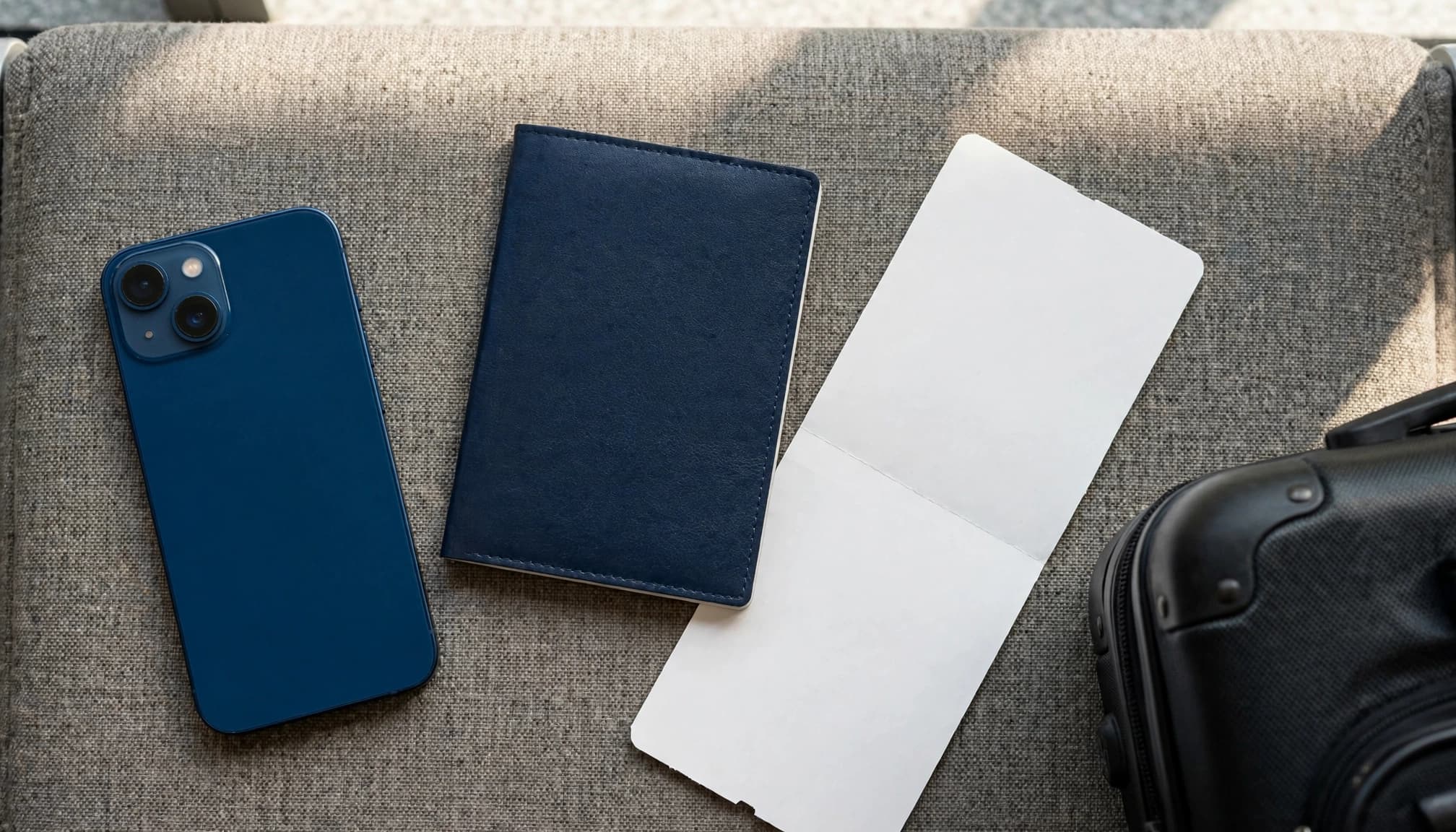 One phone, a passport, and a boarding pass arranged on an airport seat.