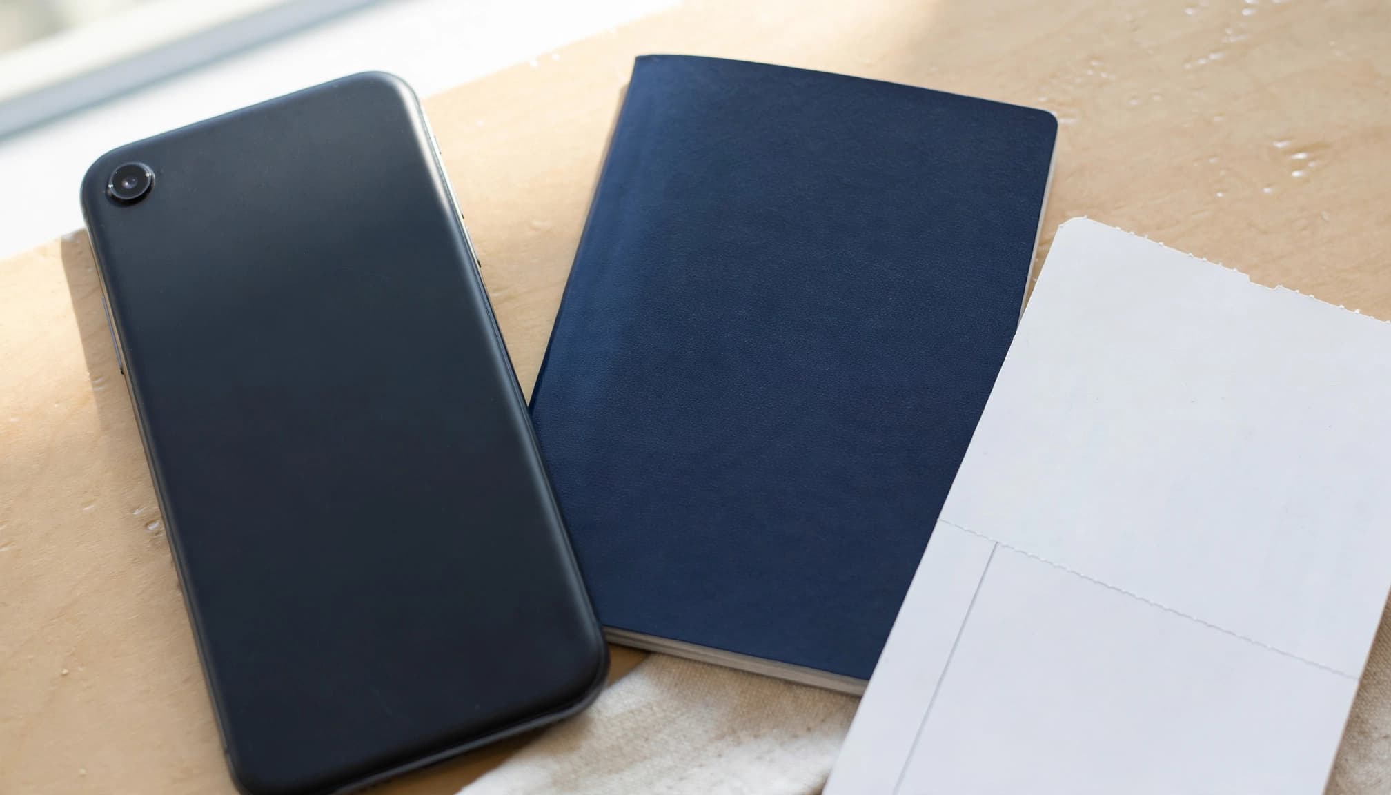 A smartphone beside a passport and boarding pass on an airport lounge table.