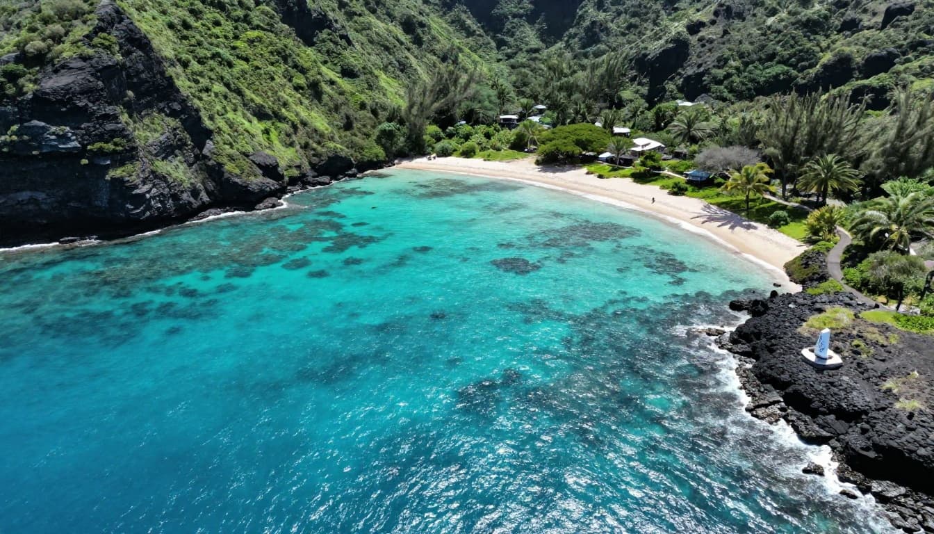 Aerial drone view of Kealakekua Bay on Big Island, Hawaii, showcasing an expansive turquoise lagoon with visible coral reefs, sand bottom, and the iconic white Captain Cook monument on black lava rock shore amid steep green volcanic cliffs.